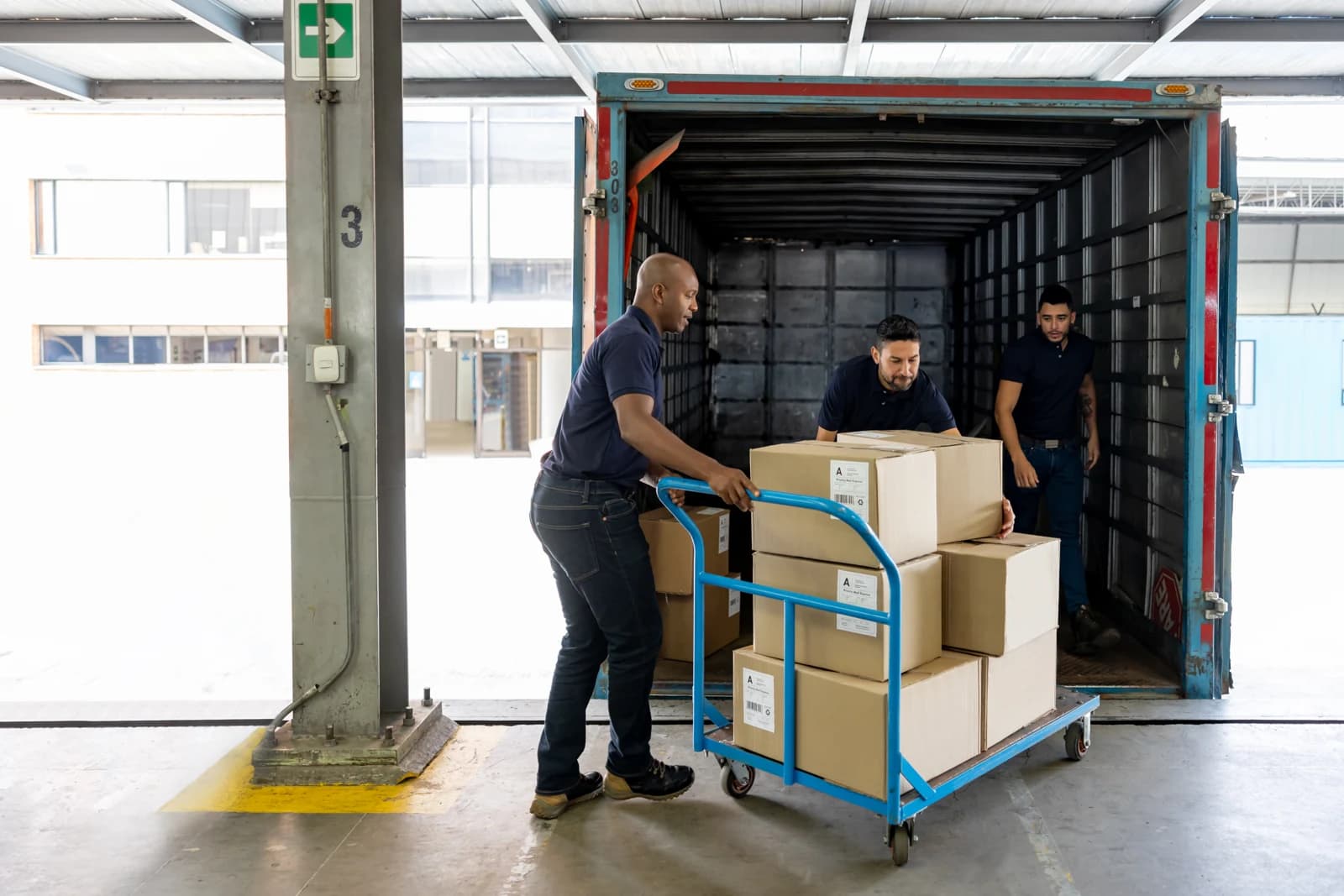 Warehouse workers loading boxed freight into a truck at the dock