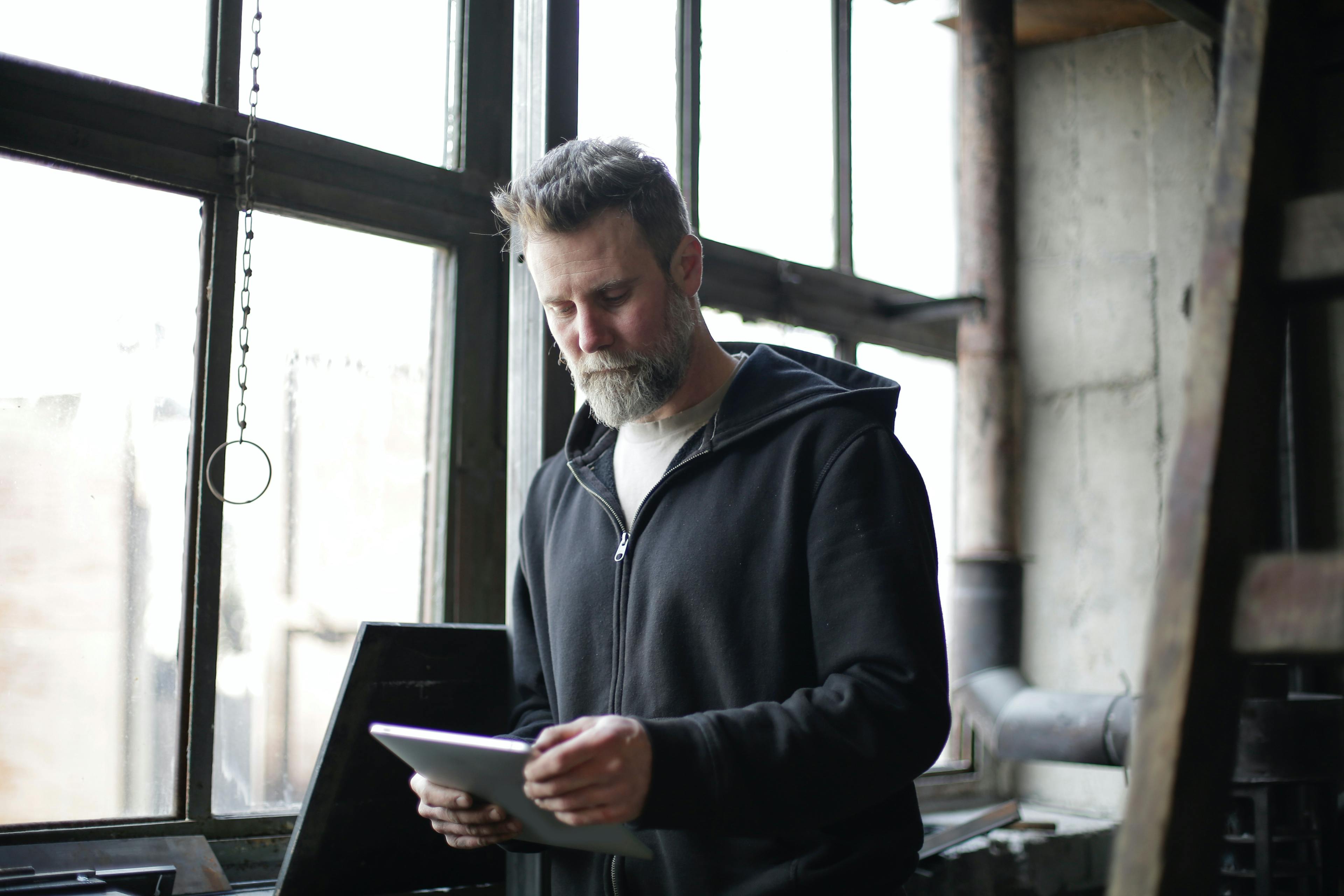 man in a hoodie holding a tablet